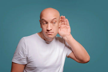 man with no hair having trouble with his hearing